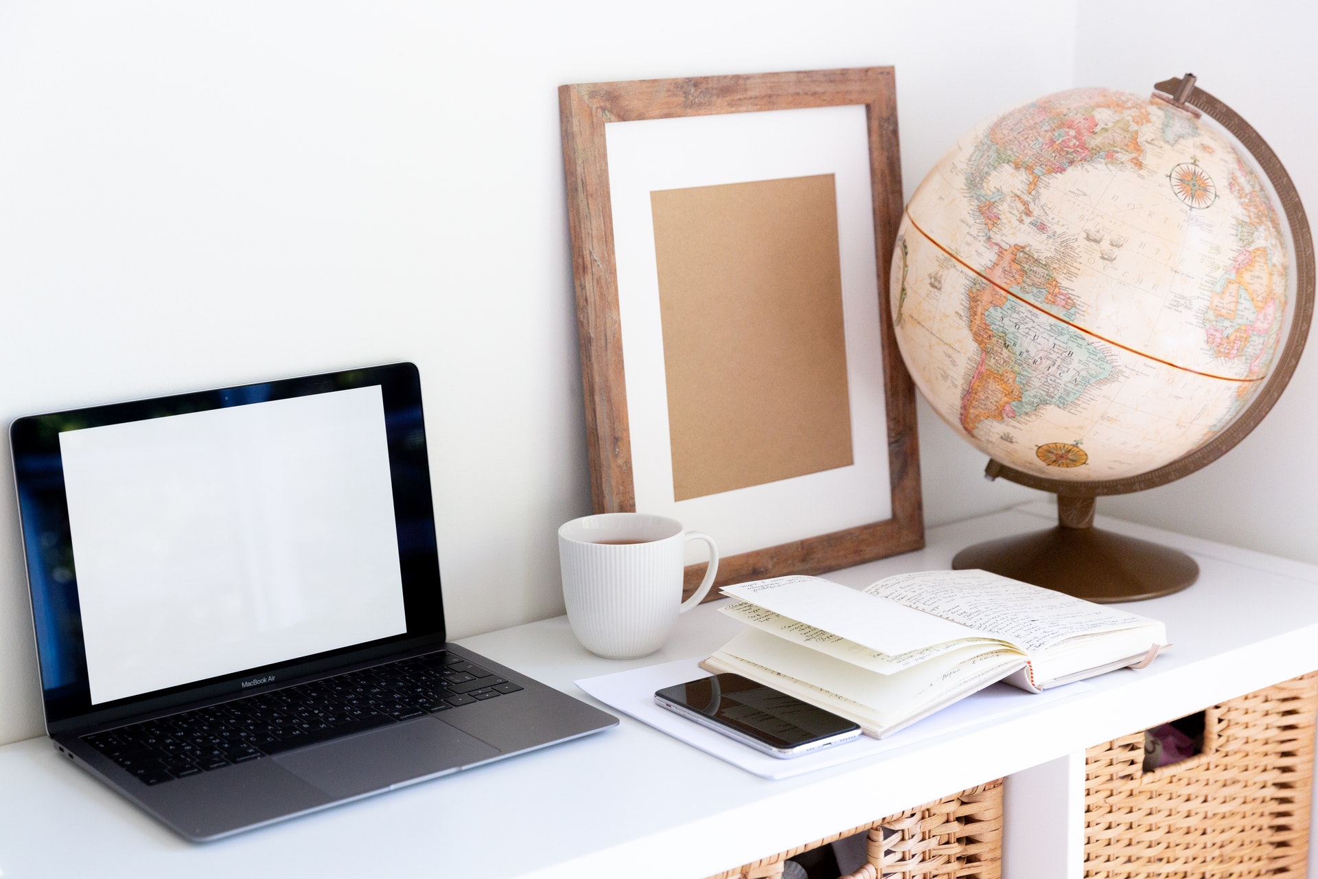 Imagem de uma mesa com um computador e um globo terrestre. Imagem ilustrativa texto internacionalização de empresas.