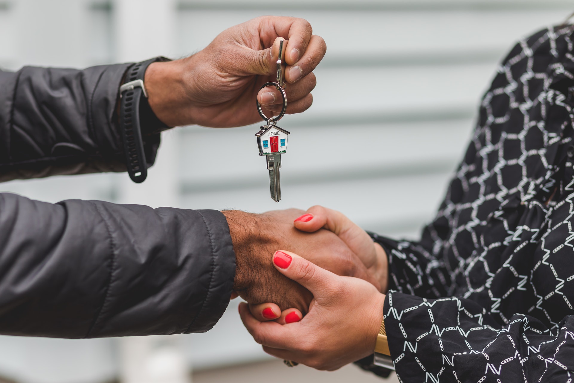 Imagem de uma pessoa passando uma chave com uma casa em miniatura para outra. Imagem ilustrativa texto melhore setores para investir.