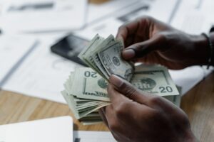 Mãos contando diversas notas de dinheiro. Imagem ilustrativa texto razões para investir em franquia.