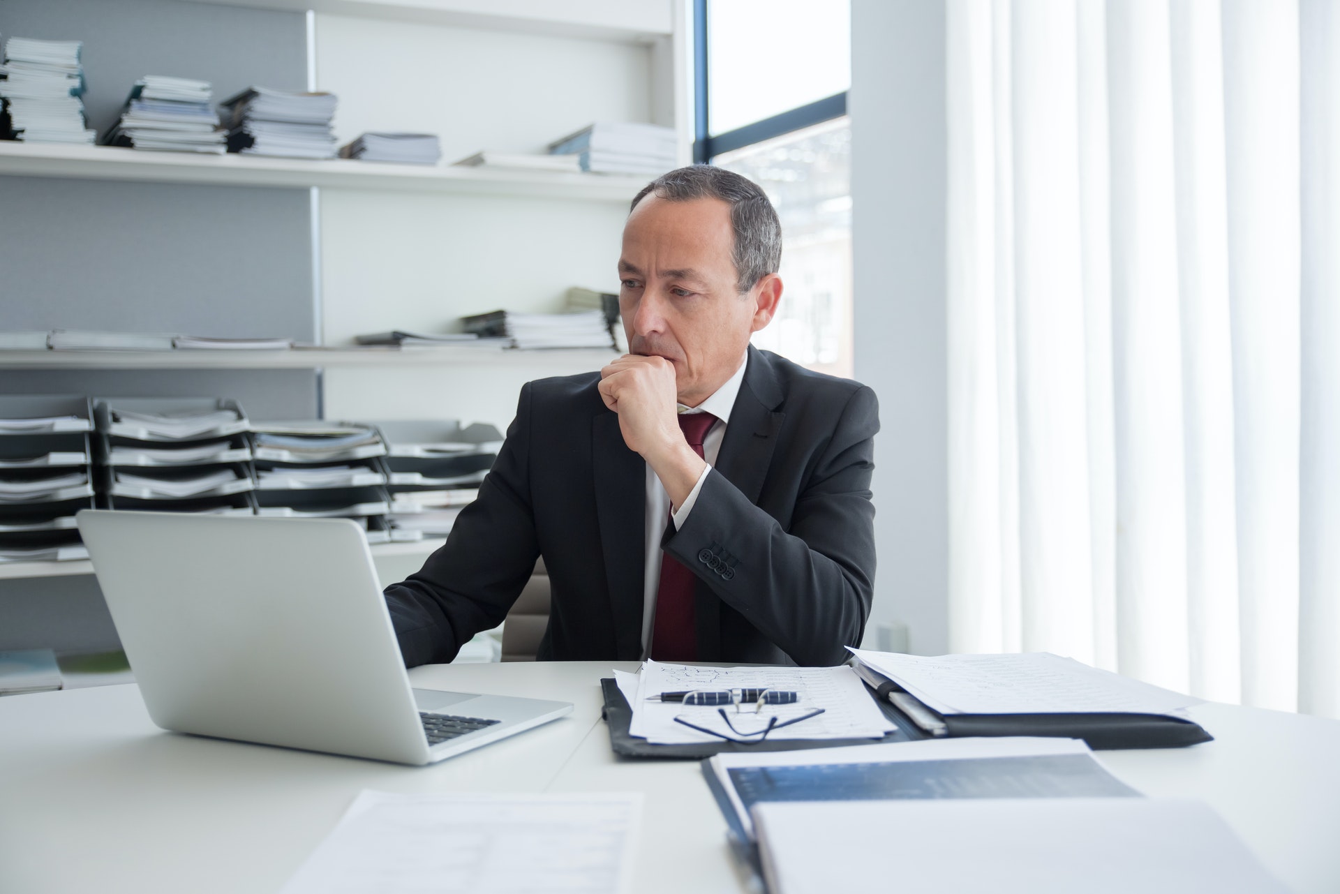 Imagem de um homem de negócios em uma mesa de escritório olhando para um computador. Imagem ilustrativa texto como investir em franquias.