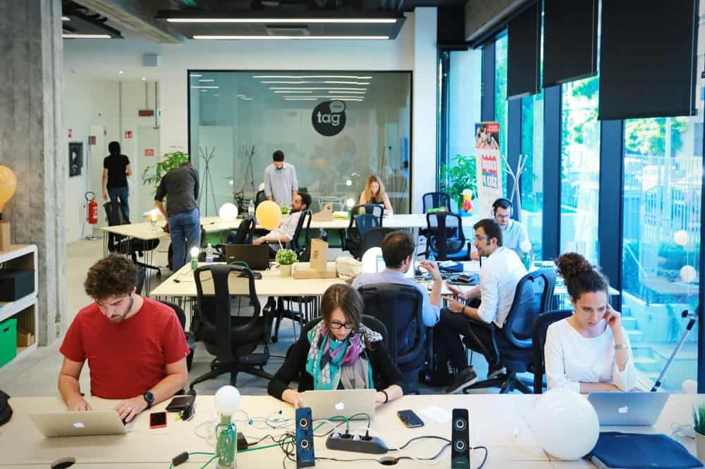 Escritório colaborativo com pessoas trabalhando em ambiente moderno e inovador, ideal para networking e crescimento profissional.