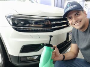 franqueado Marcos Freitas sorrindo para a câmera com borrifador na mão e em frente a um carro, mostrando seu trabalho como franqueado acquazero que abriu negócio durante apandemia
