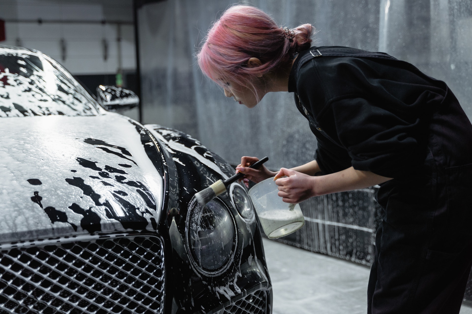 Imagem de uma mulher limpando o farol de um carro. Imagem ilustrativa do texto franquias de sucesso para investir.