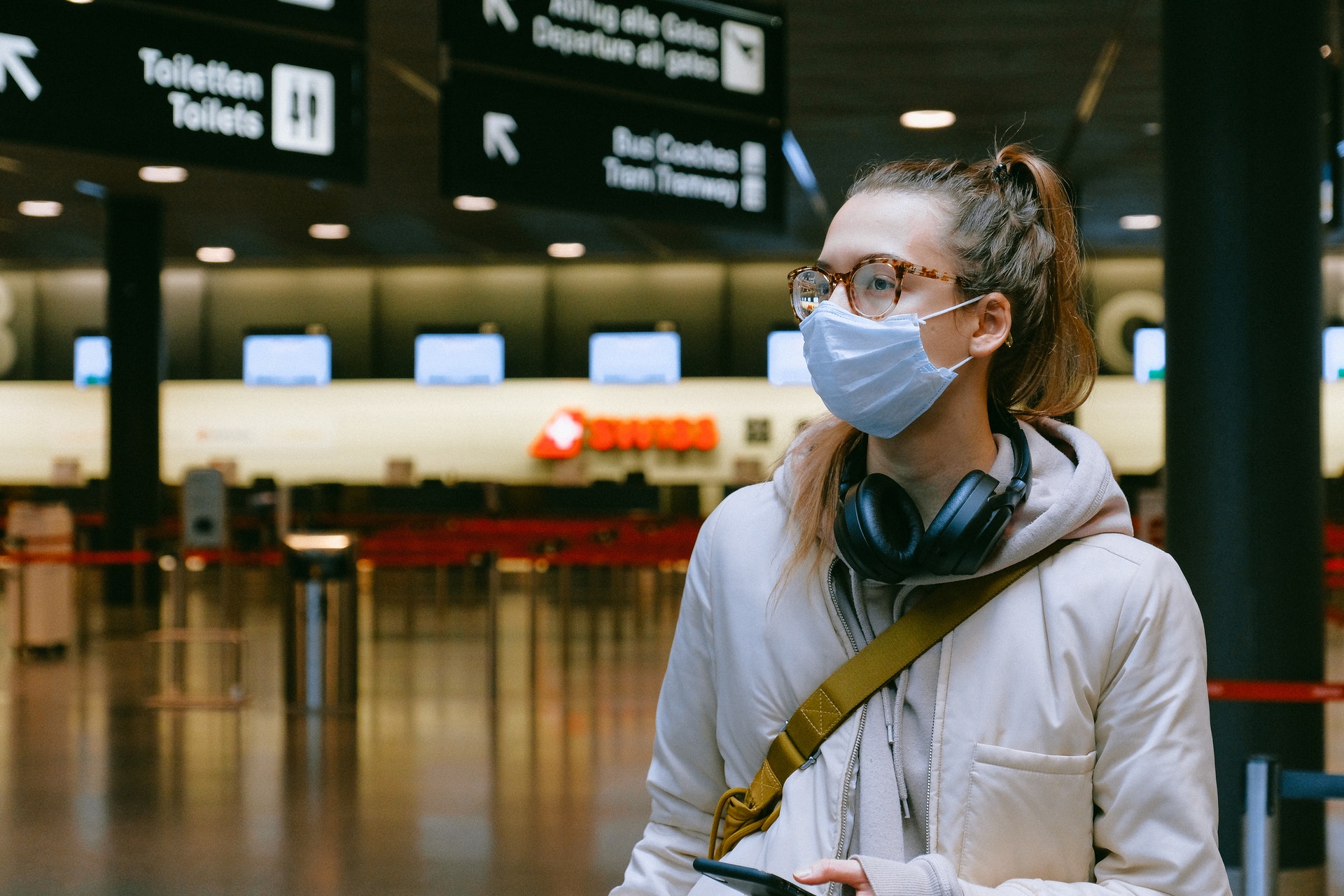 Imagem de uma mulher de máscara em um saguão de aeroporto. Imagem ilustrativa texto franquias para trabalhar online.