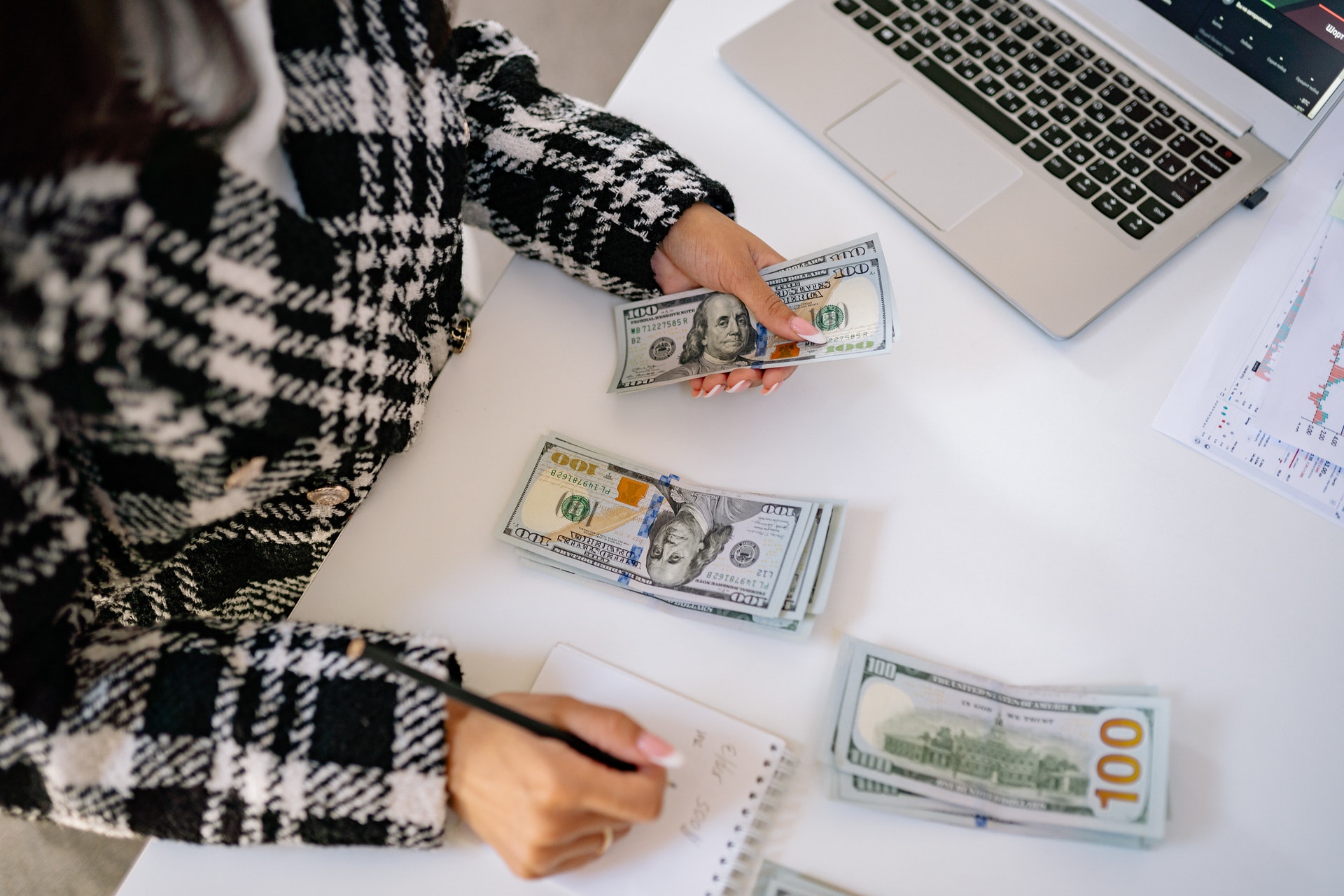 Imagem de uma pessoa em uma mesa contando notas de dinheiro. Imagem ilustrativa texto negócios lucrativos.