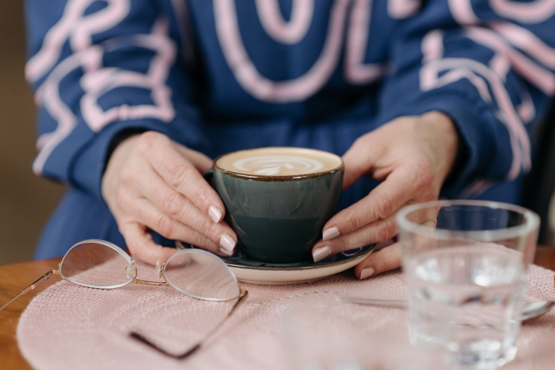 Imagem de uma pessoa segurando uma xícara de café em uma mesinha. Imagem ilustrativa texto negócios lucrativos.