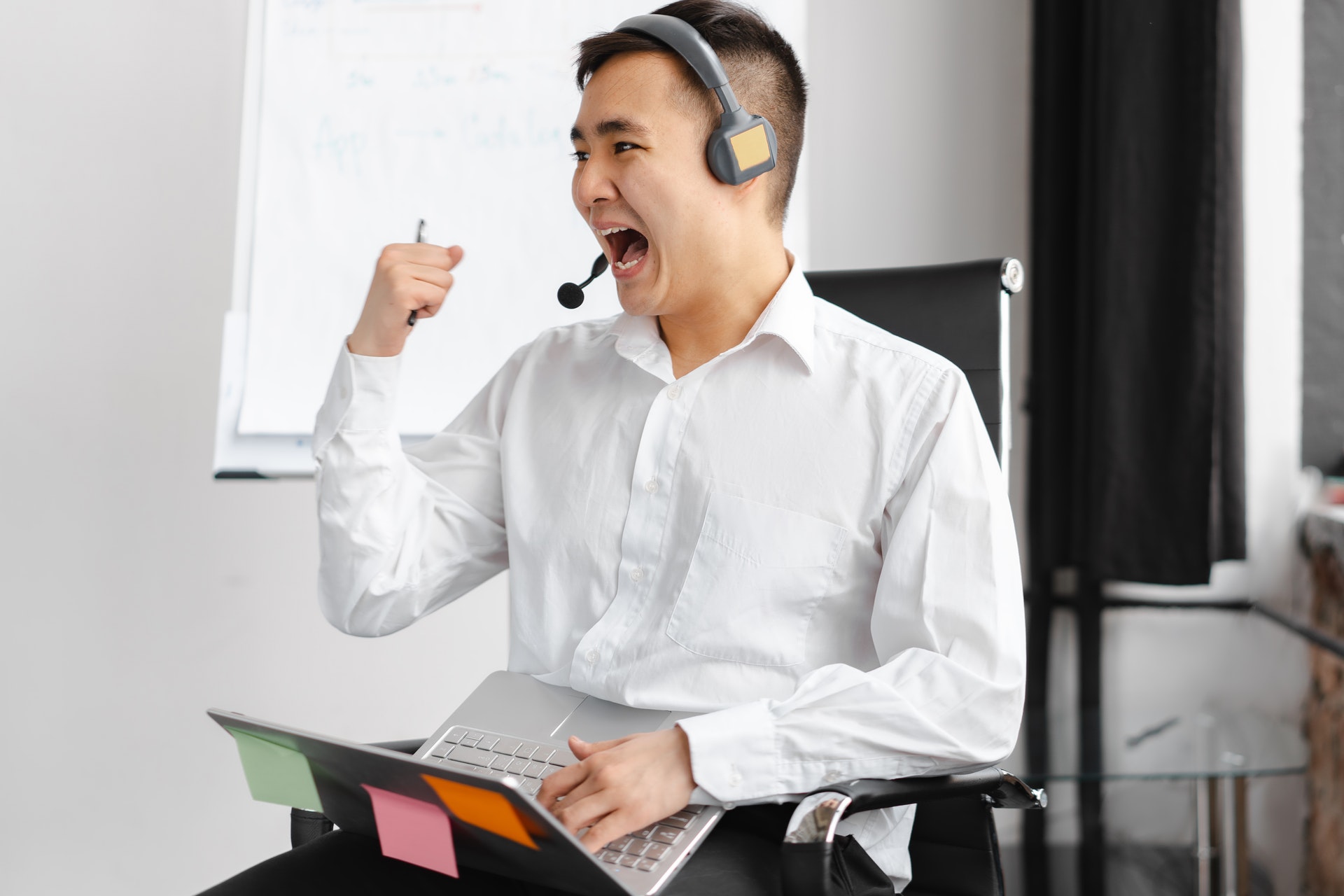 Imagem de um homem vibrando de alegria segurando um computador e com um fone de ouvido na orelha. Imagem ilustrativa texto qual negócio montar em 2022.