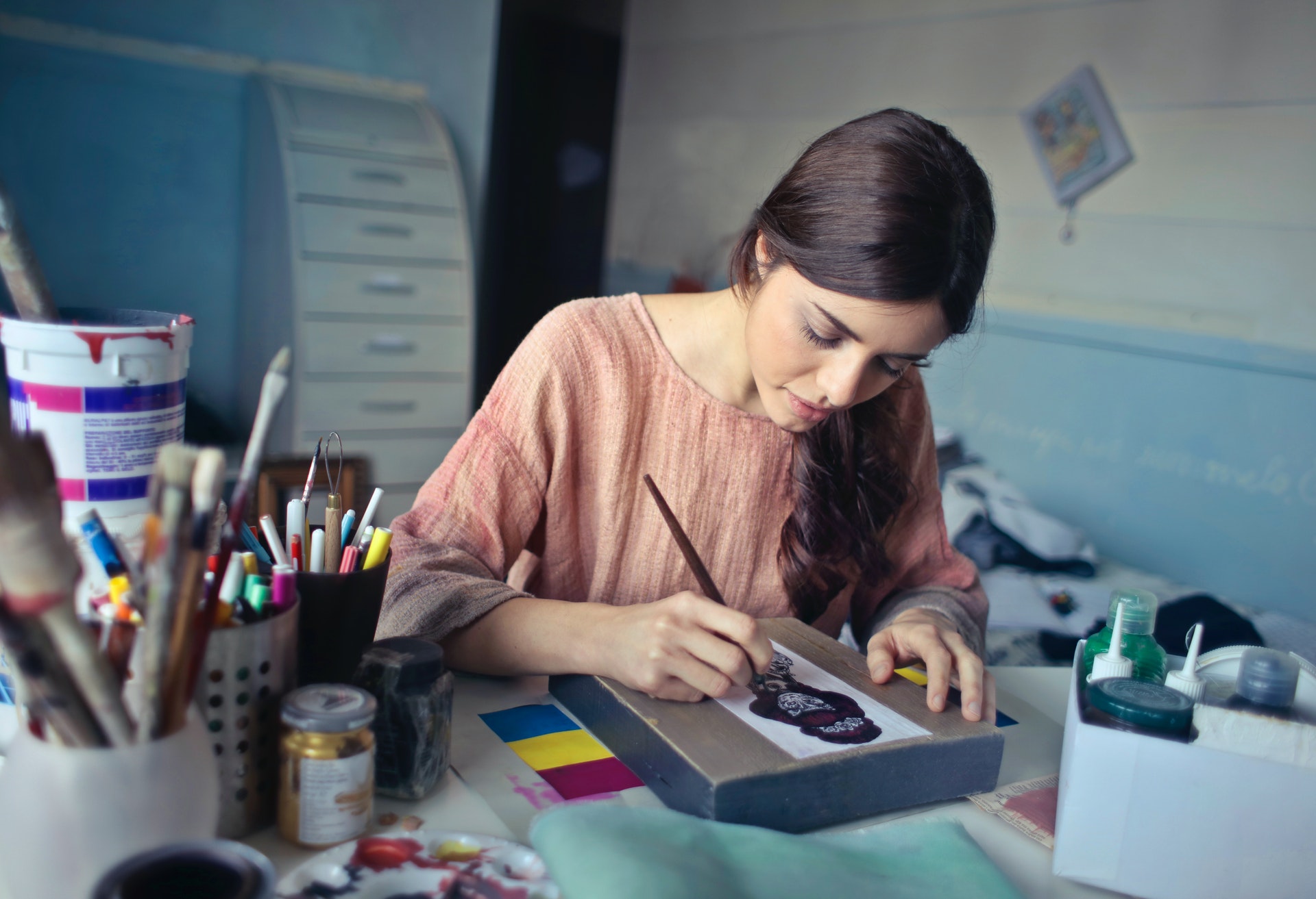 Mulher pintando algo em uma caixa. Imagem ilustrativa do texto como abrir meu próprio negócio.
