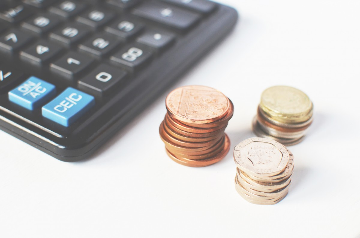 moedas empilhadas ao lado de uma calculadora imagem ilustrativa texto dicas financeiras empreender