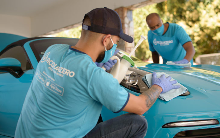 Dois técnicos da Acquazero fazendo a limpeza de um carro azul. Imagem ilustrativa do texto maiores franquias do Brasil 2021.