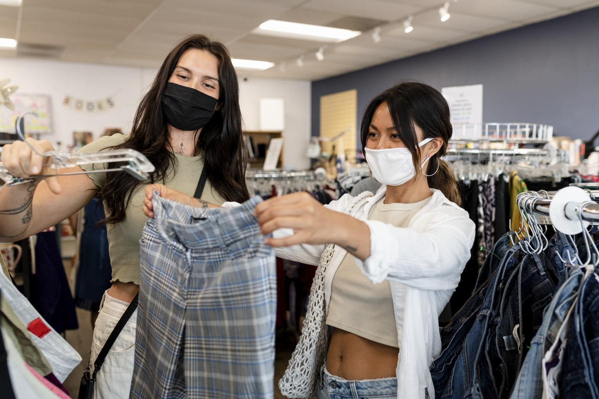 Mulheres escolhendo roupas em loja de departamento. Ilustração do texto sobre dicas para empreender.