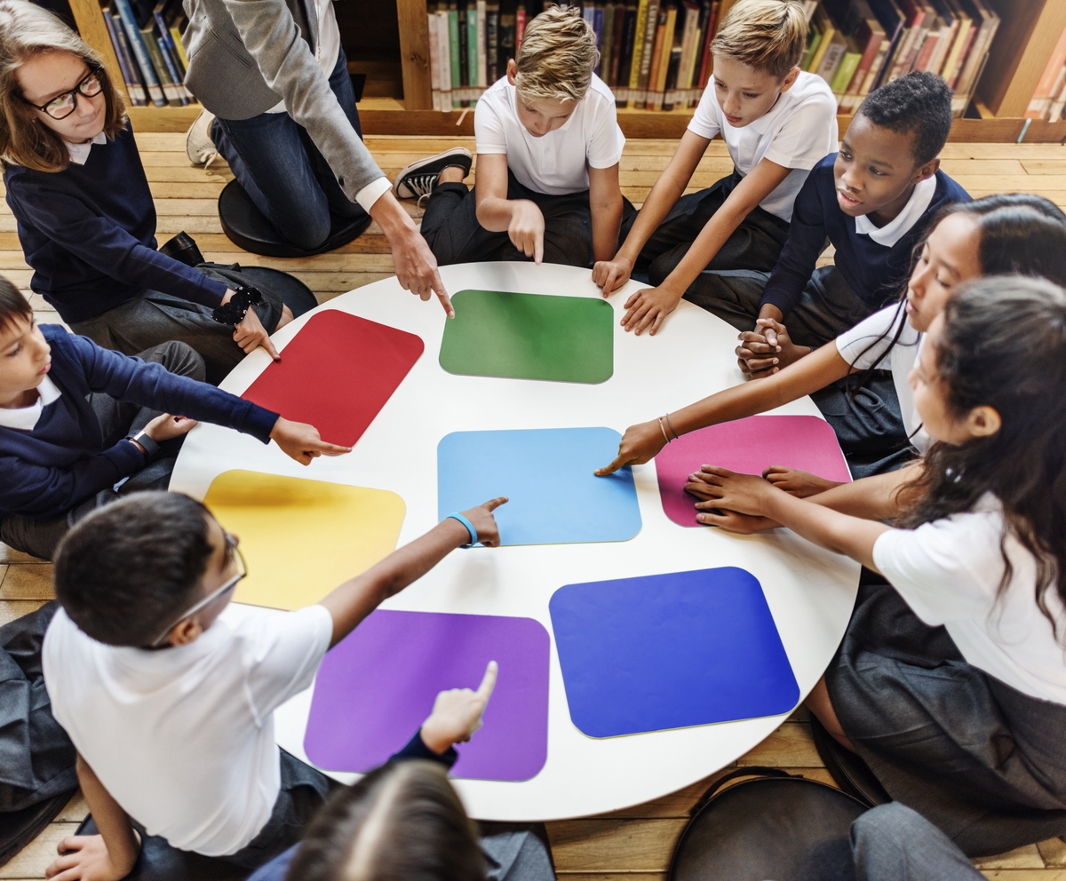 Crianças sentadas em roda apontando para imagens de cores. Ilustração do texto sobre franquia de cursos para crianças.