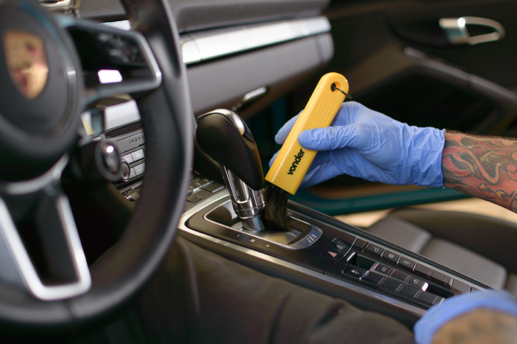 Pessoa passando um pincel limpando o interior de um carro. Imagem ilustrativa do texto investir pouco e ganhar muito.