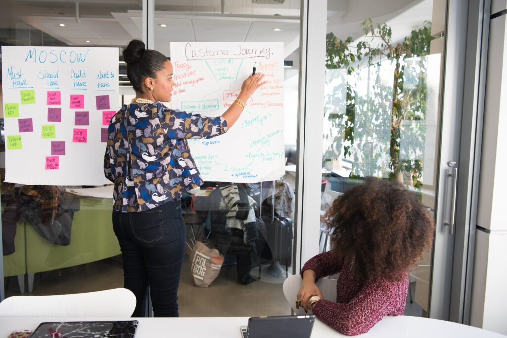 Mulheres planejando negócio usando post its colados em parede. Ilutração do texto sobre montar um negócio online.