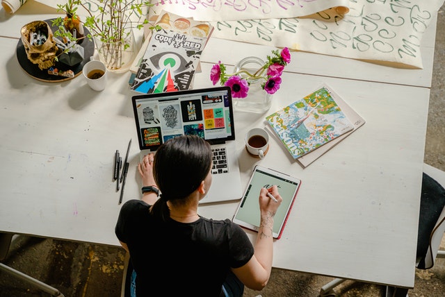 Vista aérea de mulher usando computador e tablet em mesa com livros. Ilutração do texto sobre montar um negócio online.