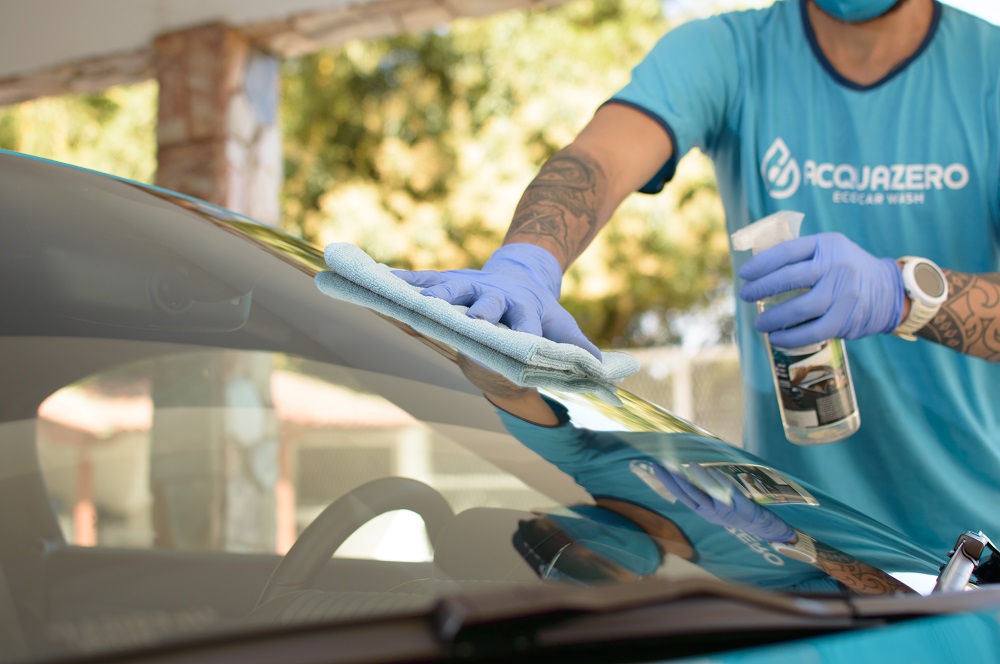 Homem higienizando carro com pano. Ilustração do texto sobre top franquias. 