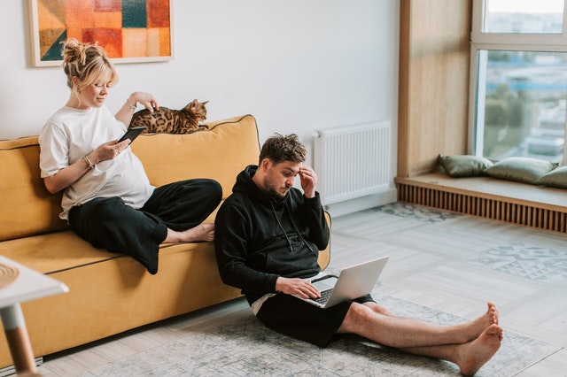 Homem sentado em chão enquanto mulher está sentada em sofá acariciando gato. Ilustração do texto sobre vida de empreendedor.