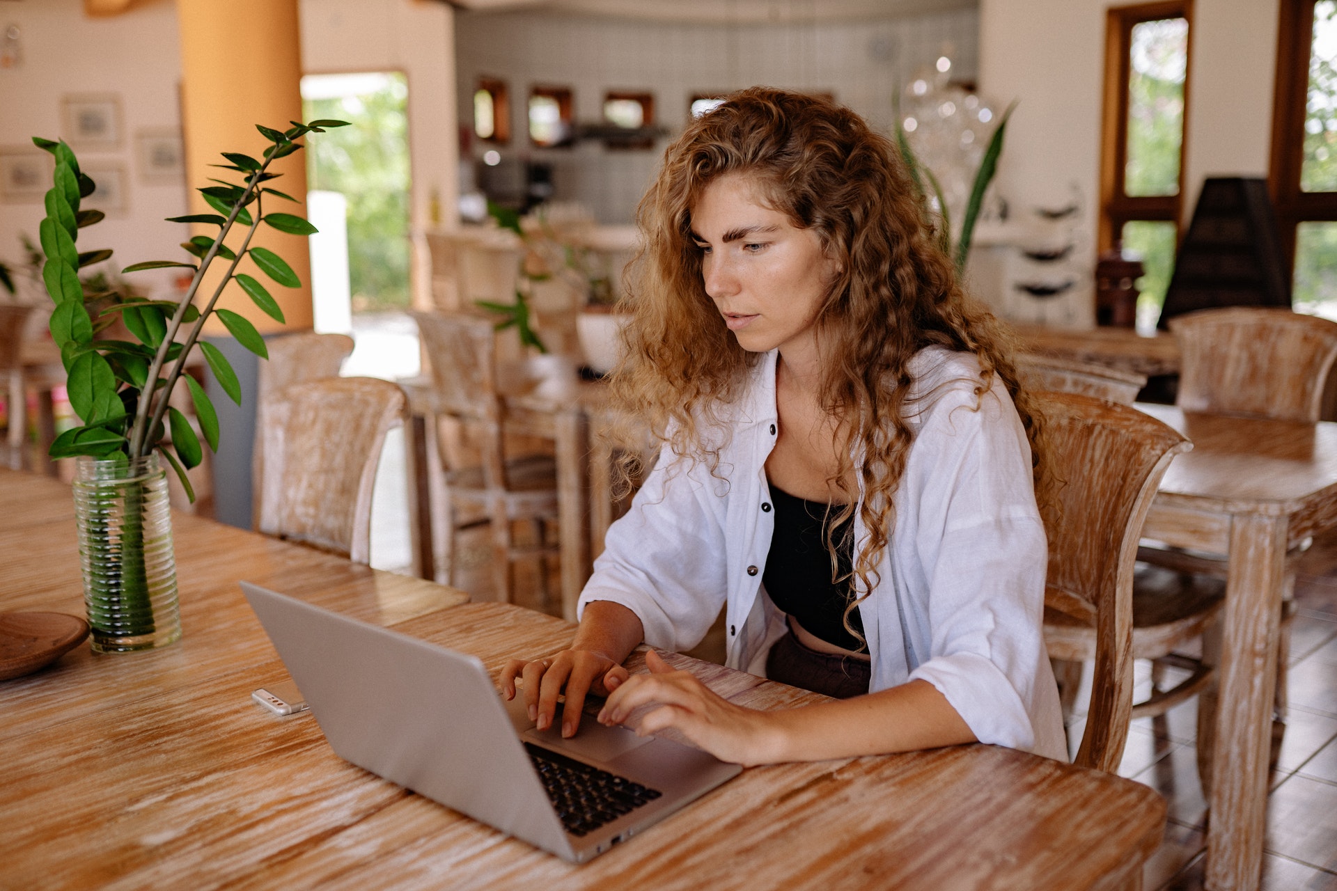 Mulher sentada em frente a um computador na copa. Imagem ilustrativa do texto empreendimentos para iniciantes.