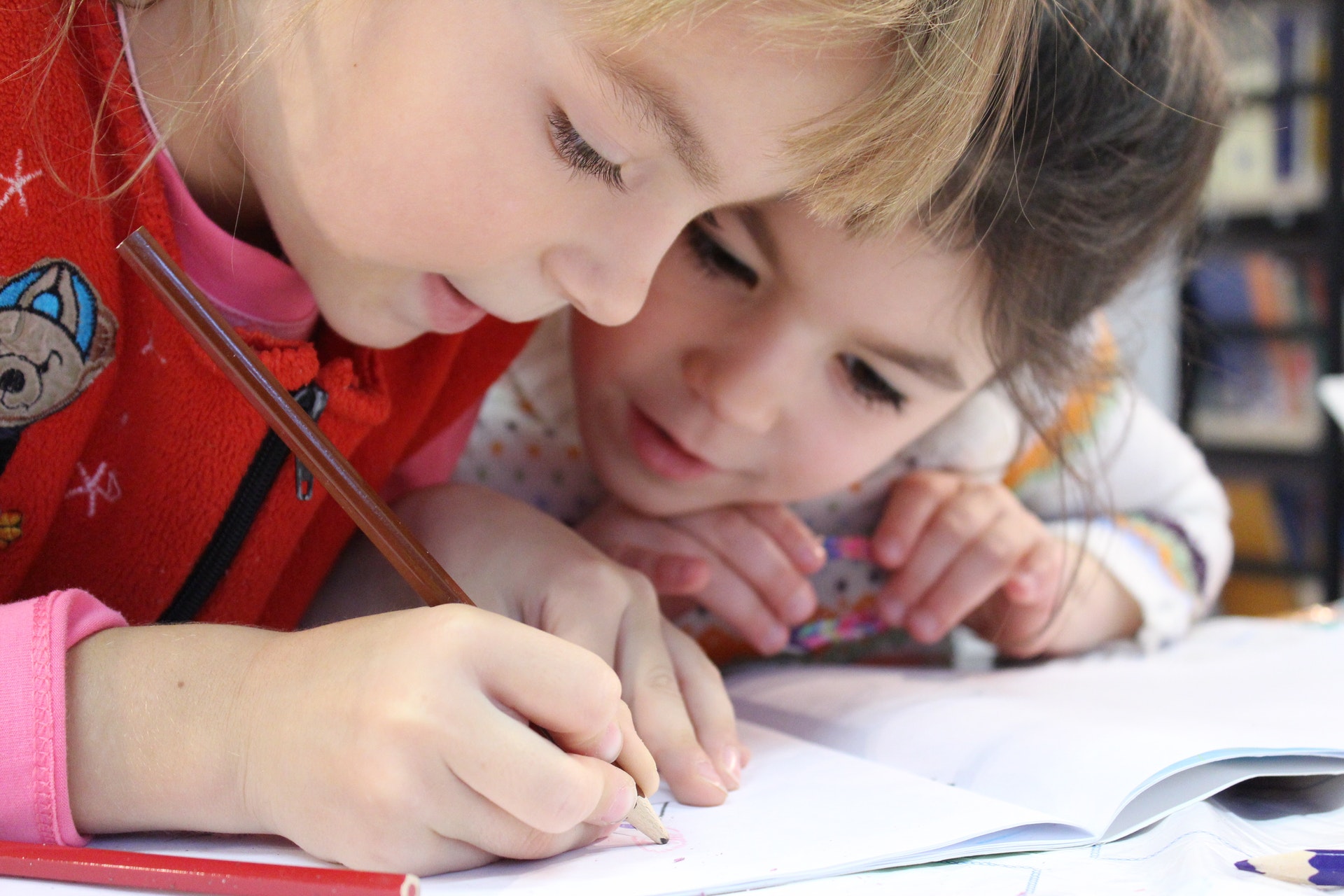 Duas crianças lendo um livro juntas. Imagem ilustrativa do texto mentalidade empreendedora das crianças.