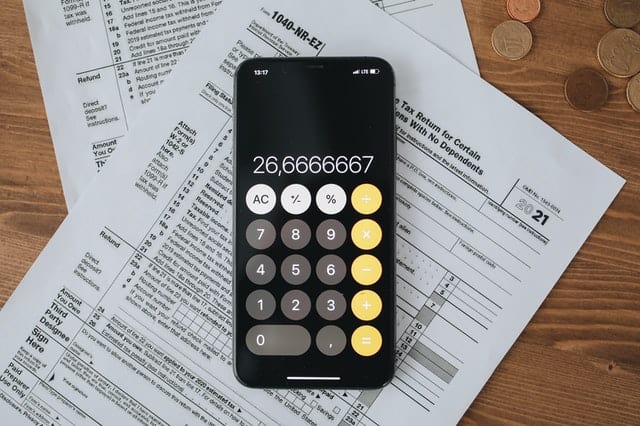Calculadora de celular em cima de papel com números. Ilustração do texto sobre como montar um negócio.