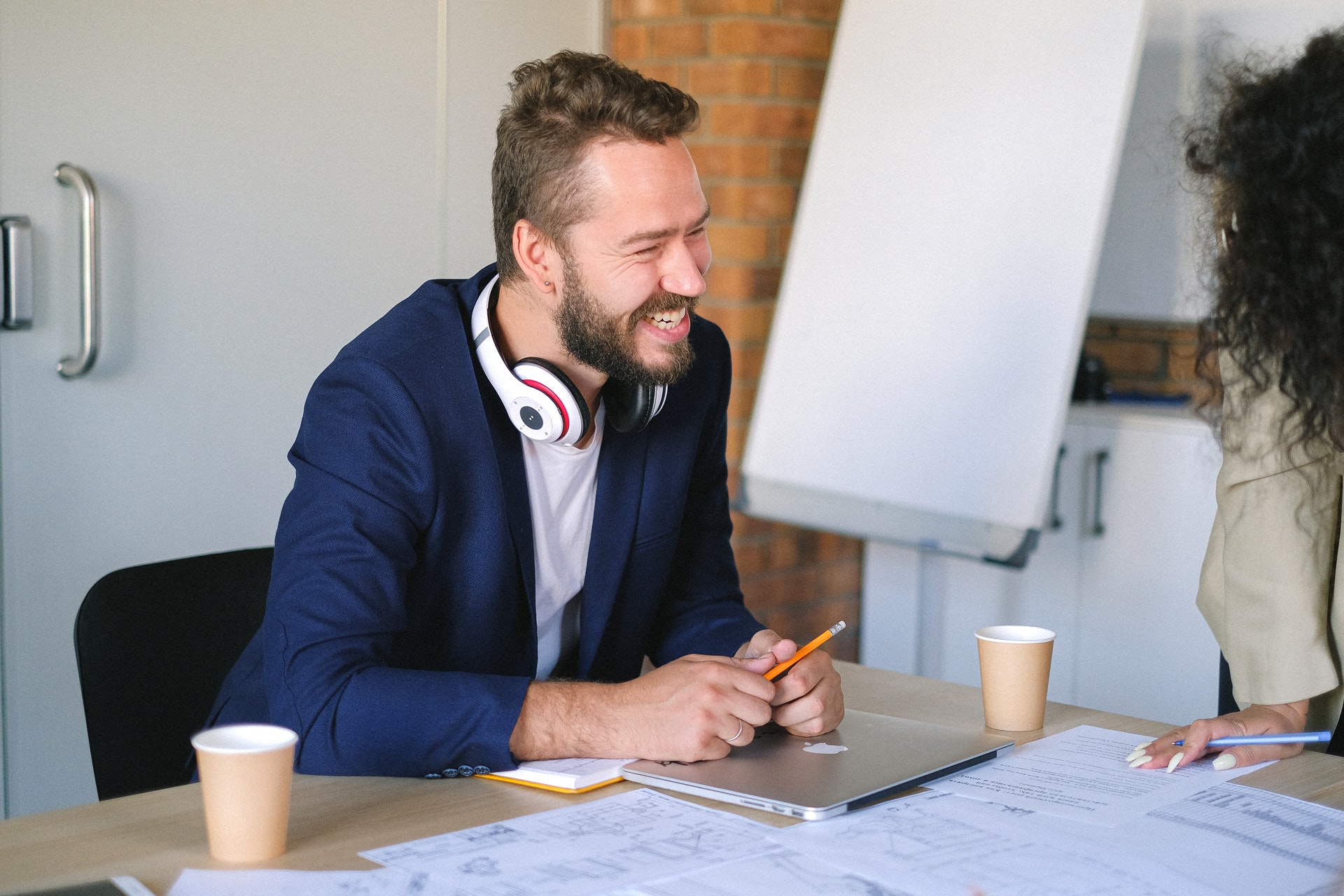 Homem com fones de ouvido no pescoço conversando com uma mulher e sorrindo. Imagem ilustrativa do texto sobre como ter um negócios de sucesso.