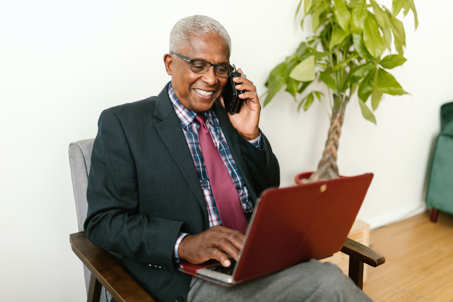 Homem sorrindo falando ao telefone e com um computador no colo. Imagem ilustrativa do texto dicas de empreendimentos.
