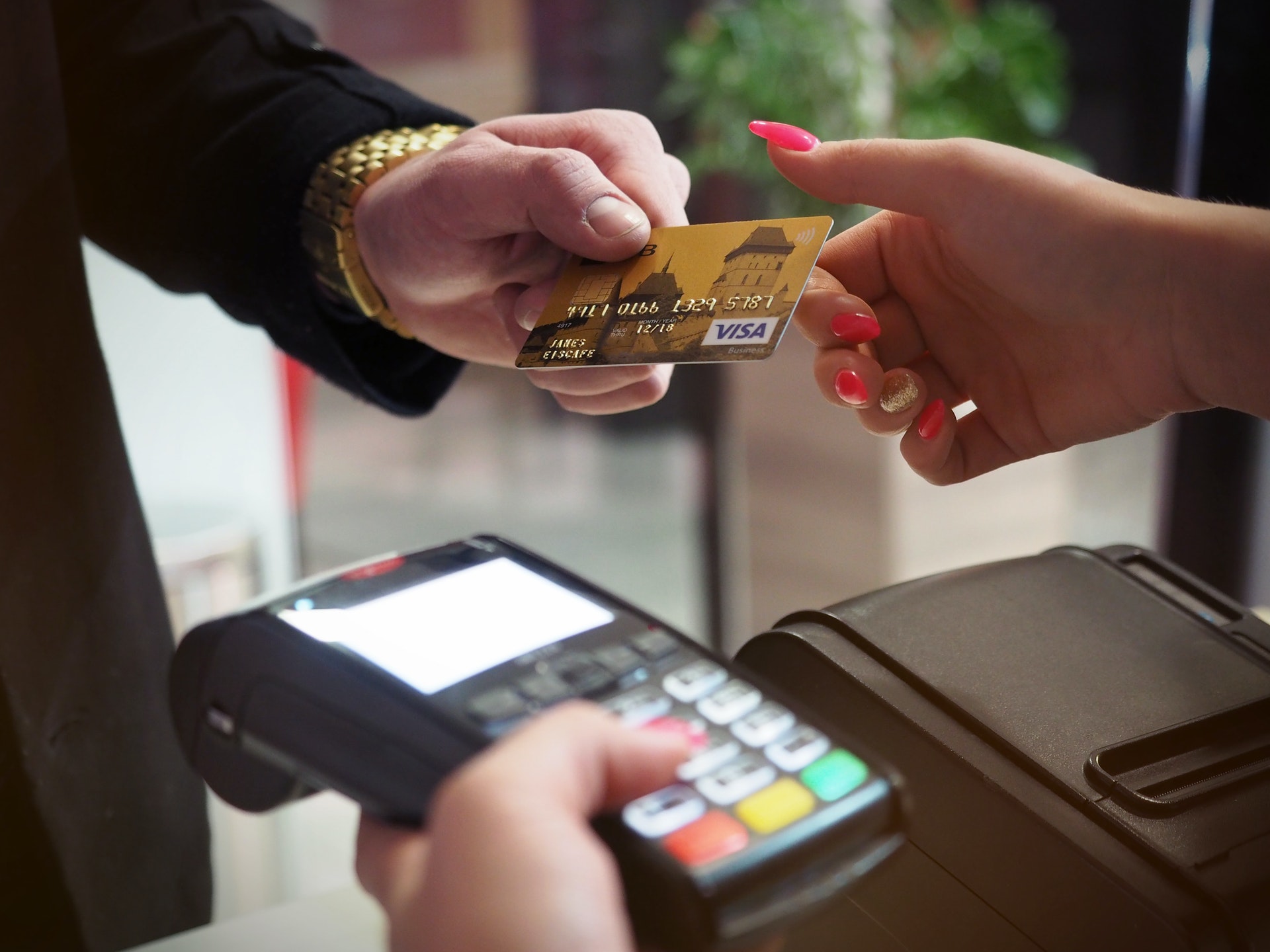 Cartão de crédito na mão e pessoa com uma máquina de cartão.