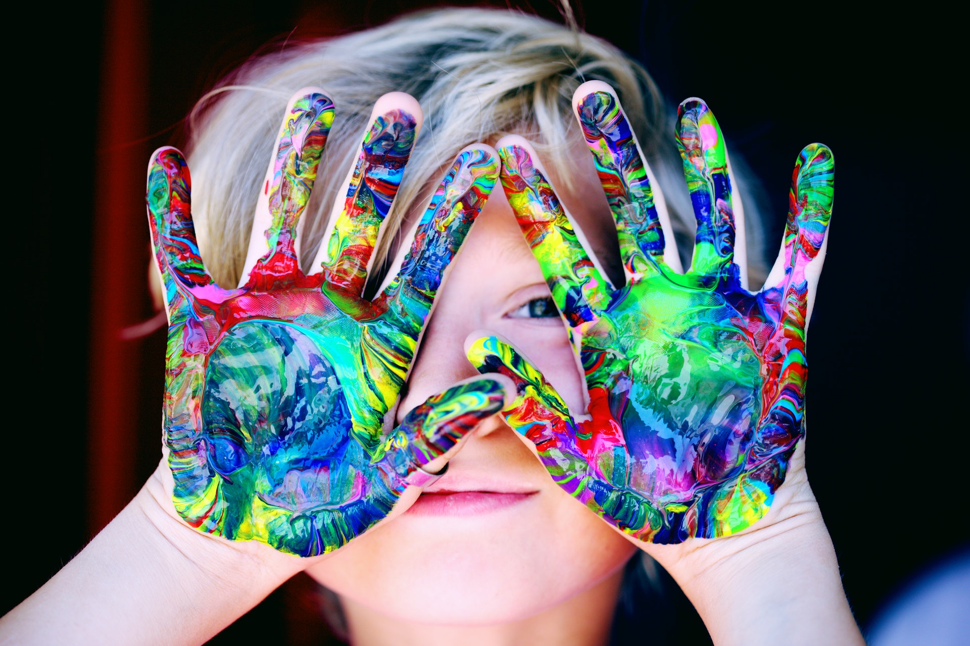 Criança com as mãos pintadas de várias cores. Imagem do texto sobre franquias interessantes e baratas.