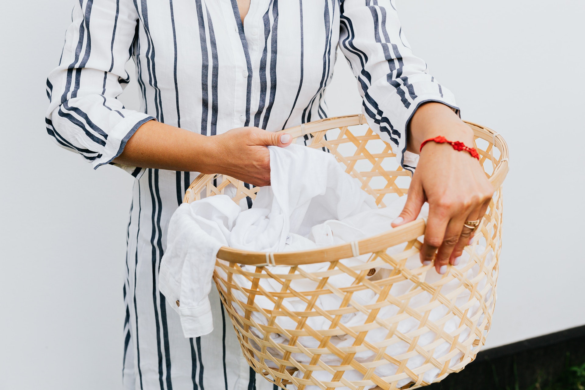 Mulher segurando um cesto de roupa com peças brancas dentro. Imagem do texto sobre franquias interessantes e baratas.