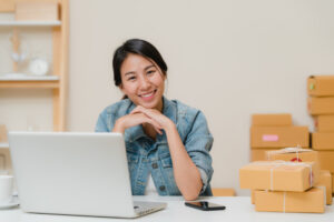 Mulher sentando em frente uma mesa com computador sorrindo. Imagem ilustrativa do texto sobre franquias online de sucesso.