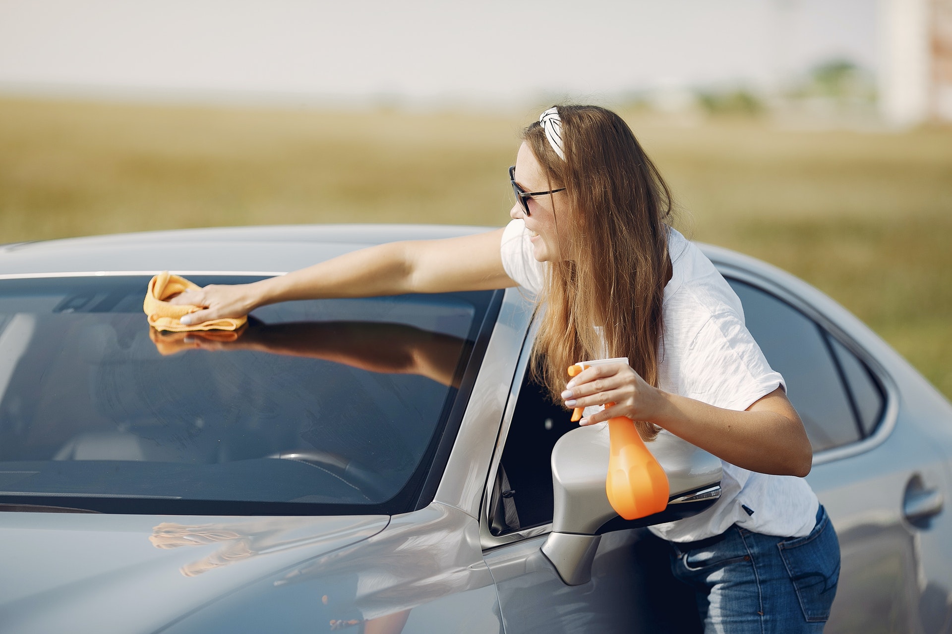 Imagem de uma mulher limpando o carro.