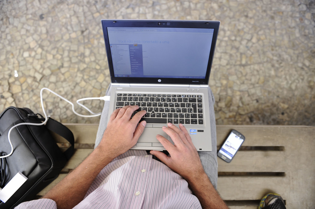 Computador no colo de uma pessoa com a mãos sobre o teclado. Imagem ilustrativa do texto sobre ideias de negócios que deram certo no exterior.
