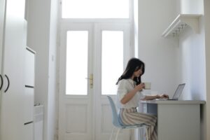 Mulher sentada em frente ao computador tomando algo em uma xícara. Imagem ilustrativa do texto as melhores e mais baratas franquias.