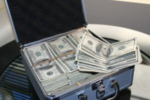 Uma maleta azul de fundo preto cheia de dólares. Imagem ilustrativa do texto investir meu dinheiro de forma segura.