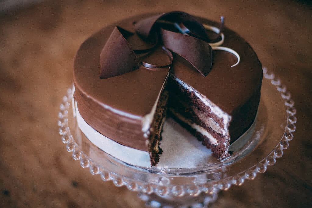 bolo de chocolate em suporte de vidro com uma fatia faltando ilustração de franquia de bolos