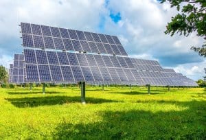 Placas de energia solar em campo com grama verde e céu azul. Ilustração do texto sobre negócio sustentável.