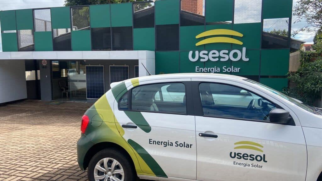 Fachada de uma loja Usesol com carro plotado da marca na frente.