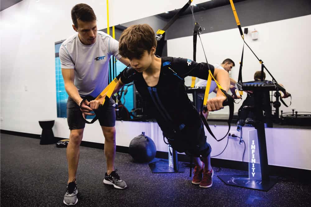 Personal trainer ajudando uma criança a fazer exercício físico em uma unidade da E-Fit.