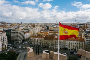 Vista aérea de uma cidade da Espanha. Observa-se bandeira amarela e vermelha. Ilustração do texto sobre abrir franquia na Espanha.