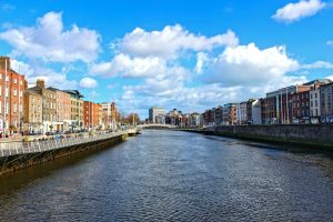Cidade da Irlanda com rio no meio e céu azul ao fundo. Ilustração do texto sobre abrir franquia na Irlanda.